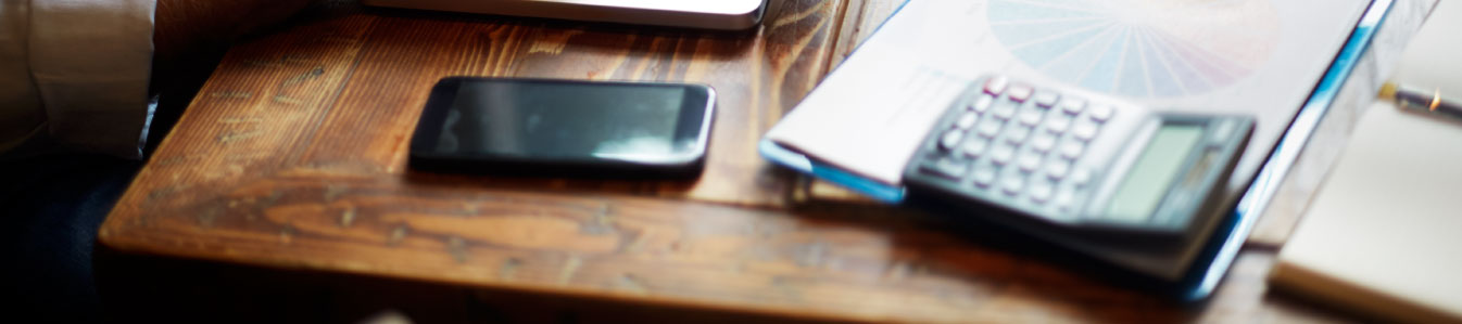 Phone and calculator sitting on wooden desk